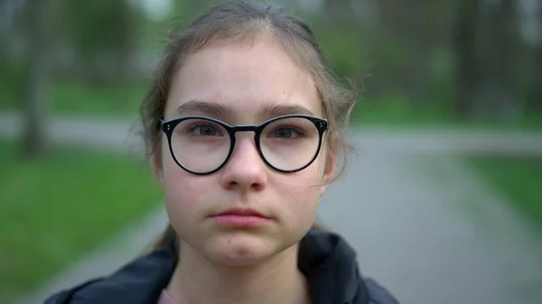 Porträt eines ernsthaften Mädchens, das im Park bleibt. Teenager Mädchen suchen Kamera im Freien. — Stockfoto