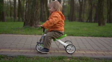 Gülümseyen çocuk bisikleti ilk deneyişinde. Dışarıda bisiklete binen mutlu çocuk.