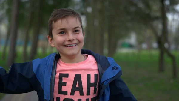 Усміхнений хлопчик-підліток дивиться камеру в парку. Щасливий хлопчик-підліток розважається на відкритому повітрі . — стокове фото