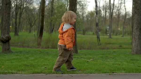 Милий малюк ходить у парку повільно. Маленький хлопчик бігає на відкритому повітрі — стокове фото