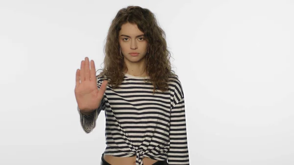 Jonge vrouw met stopbord op wit. Serieus meisje maken stop gebaar — Stockfoto