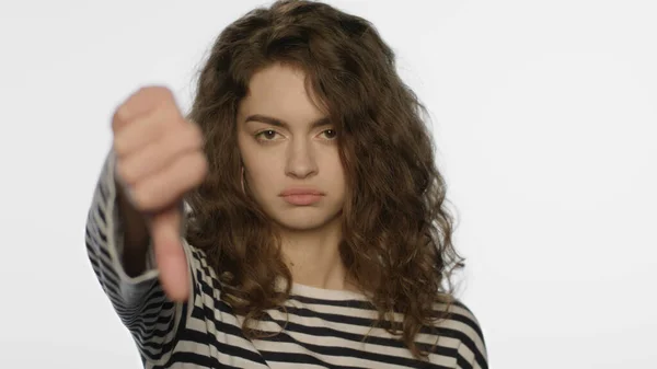 Verontrustende vrouw die duimen laat zien in de studio. Ongelukkig meisje toont een afkeer gebaar — Stockfoto