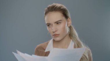 Belgelere bakan düşünceli bir iş kadını. Elinde evraklar tutan ciddi biri.