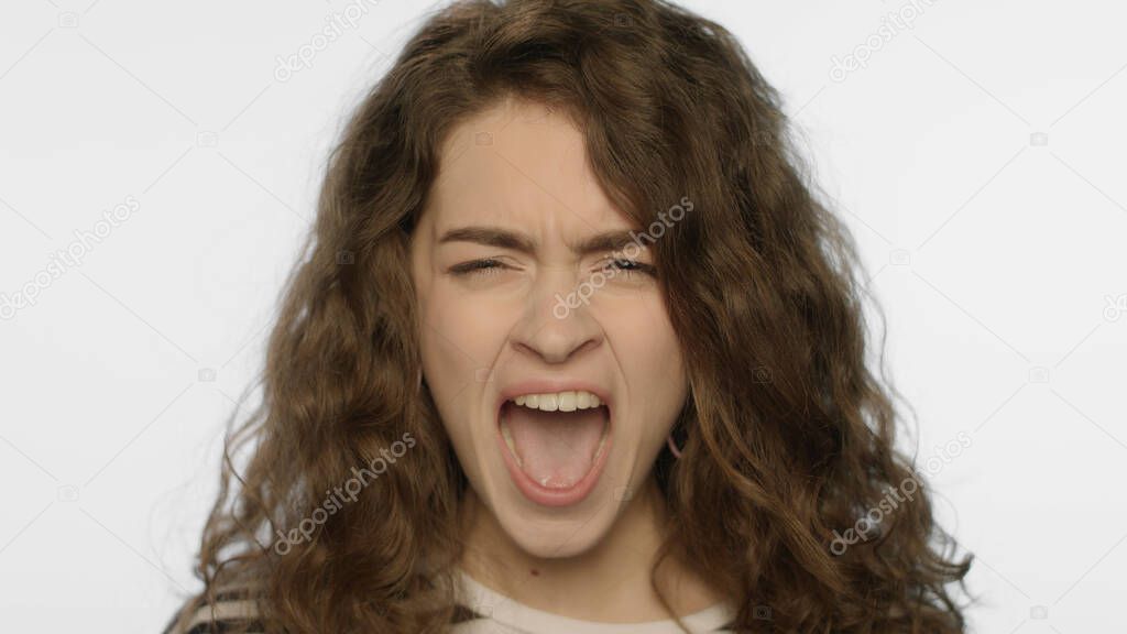 Angry woman screaming in studio. Portrait of rage girl scream on white