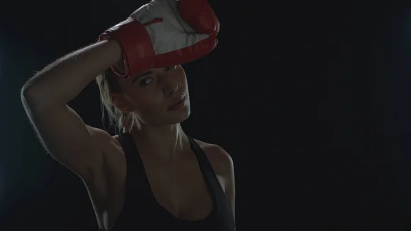Vermoeide vrouw bokser vegen zweet van gezicht na sport workout in zwart studio — Stockfoto