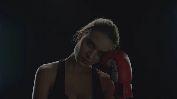 Mujer joven posando con guantes de boxeo rojos sobre fondo negro en el estudio — Foto de Stock