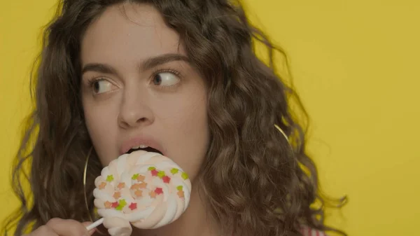 Mladá žena jí sladkosti ve zpomaleném filmu. Portrét šťastné dívky s marshmallow — Stock fotografie