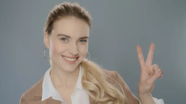 Young business woman showing v sign. Smiling businesswoman show peace sign