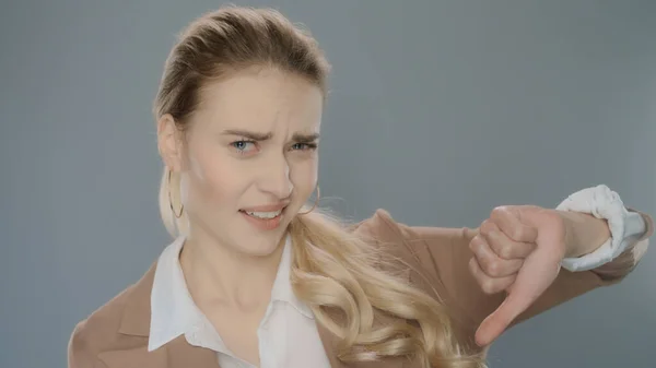 Upset businesswoman showing thumbs down in studio. Portrait of business woman