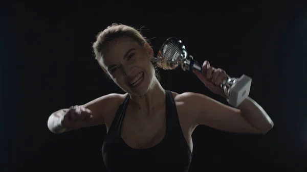 Happy woman raising up hands with champion trophy in slow motion