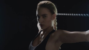 Koyu renk spor salonunda spor iple antrenman yapan bir kadın. Spor salonunda egzersiz yapan formda bir model.