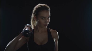 Spor salonundaki kadın siyah arka planda halter egzersizi yapıyor. Spor modeli