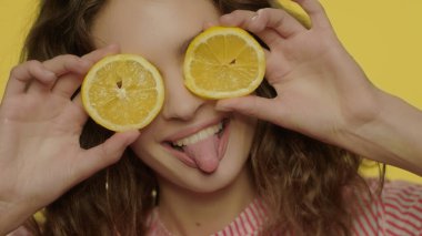 Oyuncu kız sarı arka planda limon dilimleriyle eğleniyor. Neşeli kadın.