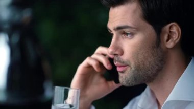 İş adamı yüzü akıllı telefondan arıyor. Erkek girişimci cep telefonu kullanıyor.