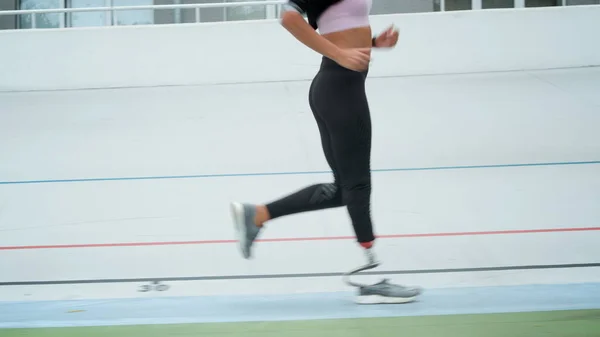 En handikappet kvinnelig jogger på veddeløpsbanen. Treningsjente utendørs – stockfoto