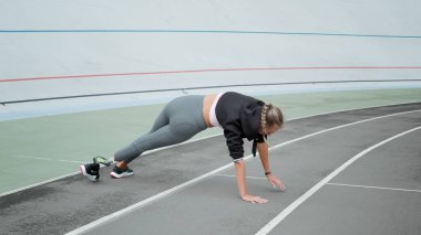 Yapay bacaklı sporcu kadın stadyumda yoga yapıyor. Bayan yolda geriniyor.