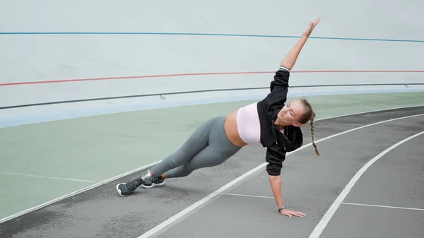 Handikappad kvinna gör planka till hands på arenan.Lady utövar på sportbanan — Stockfoto