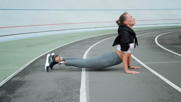 Behinderte Frau praktiziert Yoga im Sportstadion. Mädchen beim Sport im Freien — Stockfoto