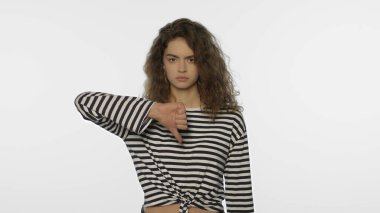 Mutsuz kadın, beyaz arka planda baş parmak aşağı duruyor. Hüzünlü bir kızın portresi.