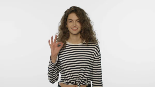 Glückliches Mädchen zeigt ok Zeichen im Studio. Porträt einer jungen Frau, die eine freundliche Geste zeigt — Stockfoto