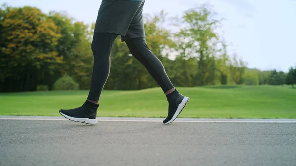 Spor ayakkabılı bir sporcu yolda koşuyor. Erkek bacakları dışarıda antrenman yapıyor. — Stok fotoğraf