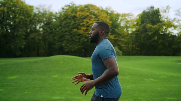 Hombre deportivo corriendo en el parque verde. Corredor haciendo ejercicio cardiovascular en la carretera —  Fotos de Stock