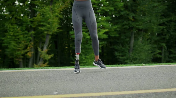 Mujer discapacitada saltando de lado en la carretera. Chica saltando en camino de asfalto — Foto de Stock