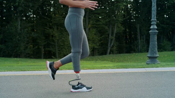 アスファルトの道路上で実行されている障害のある女性のジョギング。屋外での女の子のトレーニング — ストック写真