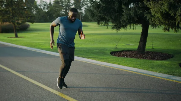 Африканський американець біжить по парку. Спортсмен проводить тренування на відкритому повітрі. — стокове фото