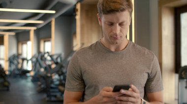 Spor kulübünde mesaj atan yakışıklı bir sporcu. Vücut geliştirici spor salonunda duruyor.