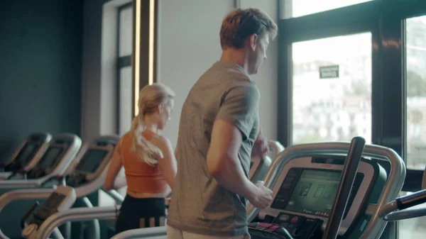 Sporty fit couple doing cardio at gym. Family running on treadmill in sport club