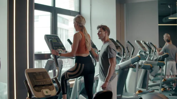Sexy fit Mädchen mit Ellipsentrainer im Sportverein. Paar trainiert im Fitnessstudio — Stockfoto