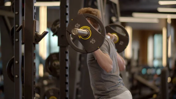 Spor salonunda halterci çömelme hareketi yapıyor. Spor kulübünde sporcu eğitimi. — Stok fotoğraf