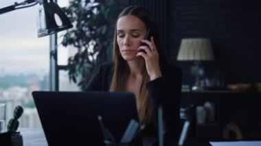 İş kadını ofisteki telefonuna cevap veriyor. Akıllı telefondan konuşan bir bayan.