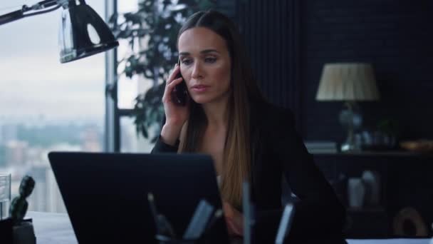 Affärskvinna pratar på smartphone på kontoret. Kvinna tittar på bärbar skärm — Stockvideo