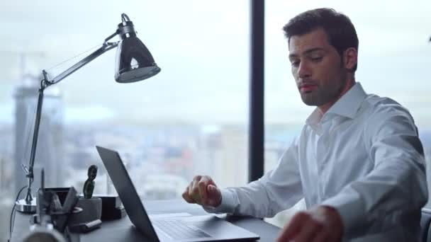 Бизнесмен делает видеозвонок на ноутбуке в офисе. Человек смотрит на графики — стоковое видео