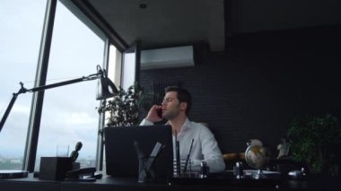 İş adamı iş yerindeki telefonuna cevap veriyor. Yönetici akıllı telefondan konuşuyor.