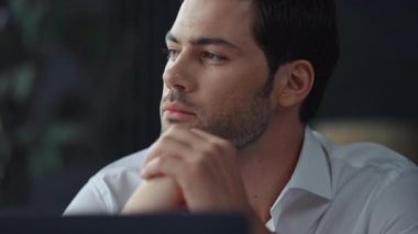 Uzak bir iş yerinde dizüstü bilgisayarla oturan düşünceli bir işadamı.