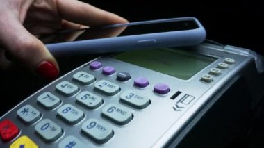 Müşteri, NFC teknolojisiyle pos terminali üzerinden cep telefonuyla ödeme yapıyor.