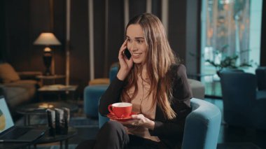 Smiing denen kadın otel salonundan cep telefonunu arıyor. Akıllı telefondan konuşan iş kadını.