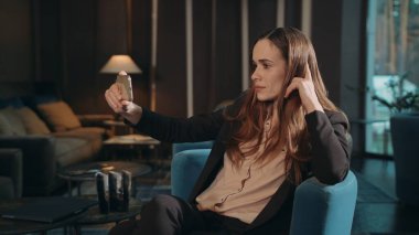 İş kadını, oturma odasında akıllı telefondan cep telefonuyla selfie çekiyor.