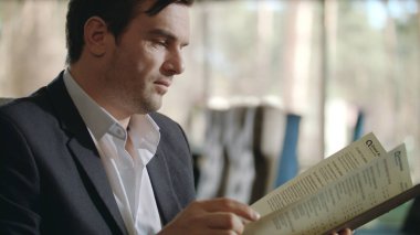 Restoranda yemek menüsünü seçen bir iş adamı. Şarap kartı arayan bir iş adamı.