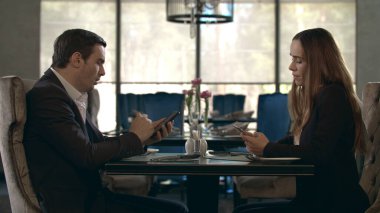 Restoranda cep telefonu kullanan bir çift. Akıllı telefonları olan çift.