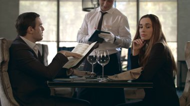 Restoranda menü okuyan yakışıklı bir adam. İş çifti kafede yemek sipariş ediyor.