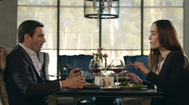 Restoranda yemek yiyen mutlu çift. Kadın akşam yemeğinde erkek tabağından yemek yiyor.