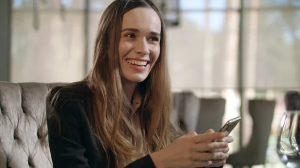 Excited woman using smartphone in restaurant. Business woman enjoy good news