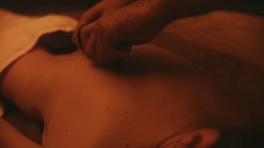 Yakından sıcak taşlarla rahatlayan güzel bir kadın. Erkek eller masajcı genç kız