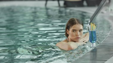 Kadın bilardoda kokteyl içerek rahatlıyor. Kaplıca havuzunda yüzen bir kadın