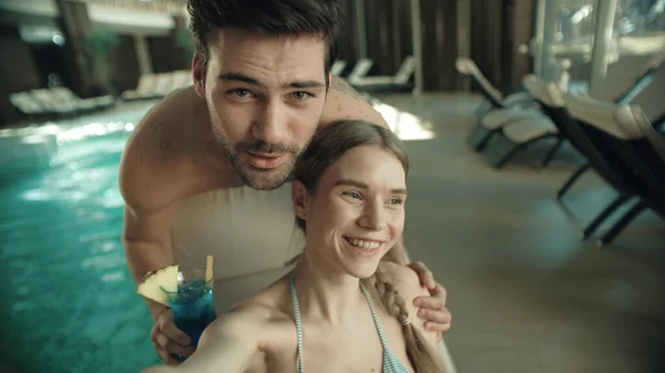 Primer plano feliz pareja teniendo videollamada por la piscina. Hombre sonriente bebiendo cóctel . —  Fotos de Stock