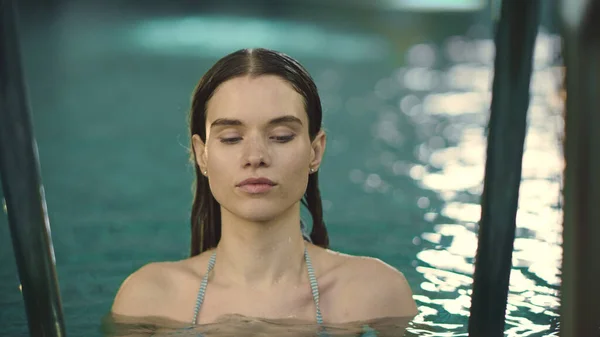 Een close-up vrouw die in de camera kijkt bij het zwembad. Meisje baden zwembad in slow motion — Stockfoto